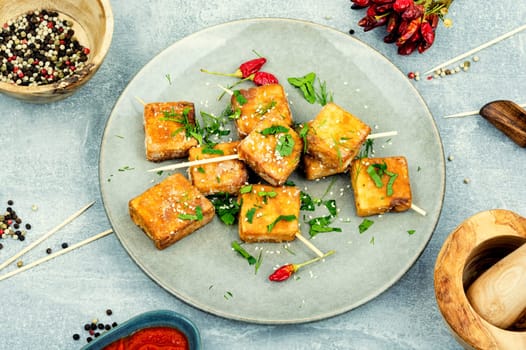 Skewers with roasted tofu cheese with and sesame seeds. Close up