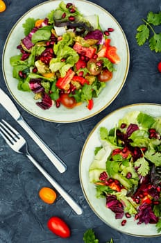 Vitamin salad with greens, pepper, red lettuce and cucumber, decorated with pomegranate.