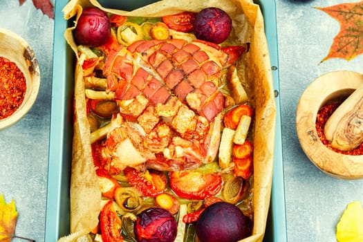 Juicy pork shoulder with skin and bacon fried with vegetables and plums.