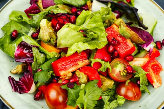 Vitamin salad with greens, pepper, red lettuce and cucumber, decorated with pomegranate.