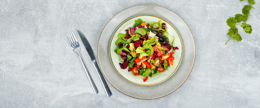 Vitamin salad with greens, pepper, red lettuce and cucumber, decorated with pomegranate.