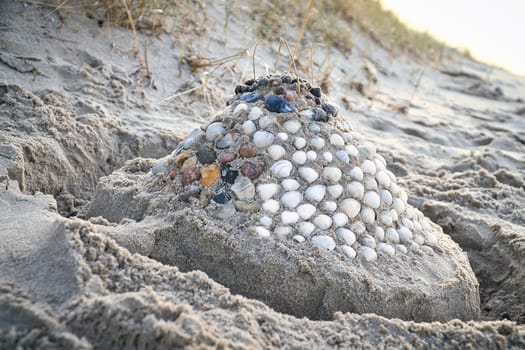 Sand castle with shells and sand. Moat around the castle in front of dunes. On the beach in Denmark by the sea. Landscape photo