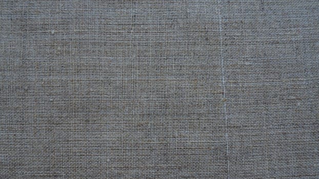 Fabric texture background. Gray fabric with weave. Natural slightly wrinkled look of the material. Uniform copy space background. Cotton, canvas or woolen thin fabric laid evenly on the surface