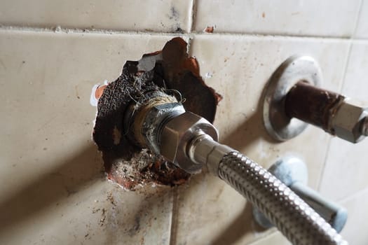 Replacement of the hot water pipe coming from the boiler. New hose. Broken tiles on the wall. Water leakage, accident and plumbing work with the opening of the wall in the bathroom or kitchen