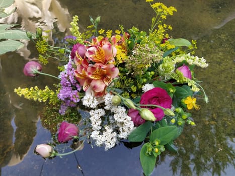 pink and red roses in a bouquet floating in the water of a fountain. Plucked buds as decoration for a summer holiday. Ivan Kupala, summer solstice. Harvest festival