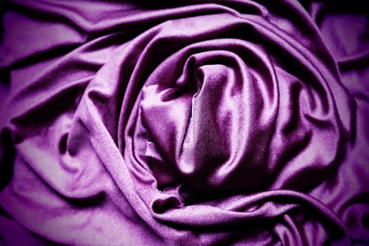 Velour fabric, similar to silk. Textiles in a folds, beautiful waves, twisted into a circle. Purple, pink, magenta shades on the drapery. Sewing material for dresses, furniture upholstery, curtains