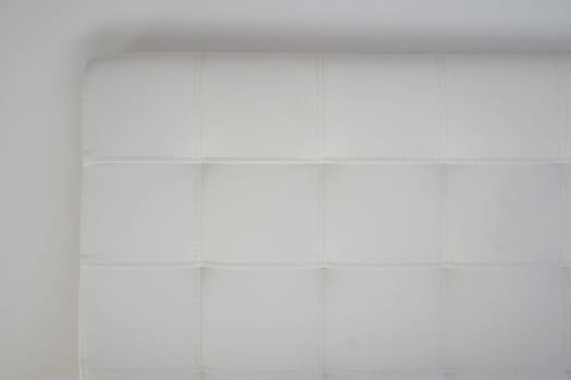 Soft headboard. Upholstery for furniture made of genuine or artificial leather and fabric. Soft headboard against a light wall