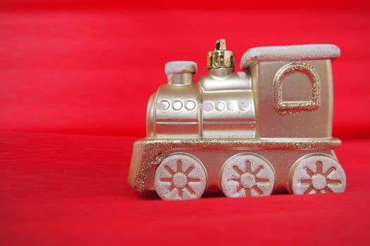 Golden toy train locomotive on a red and pink gradient background. New Year or Christmas card. Icicles and snow on a train. Free space for text. Copy space. Festive background