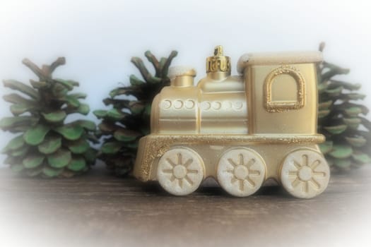 Golden children's toy train. Cones painted with green gouache Christmas trees. New Year or Christmas card. Icicles and snow on the train. Festive background. Christmas decorations. White vignette