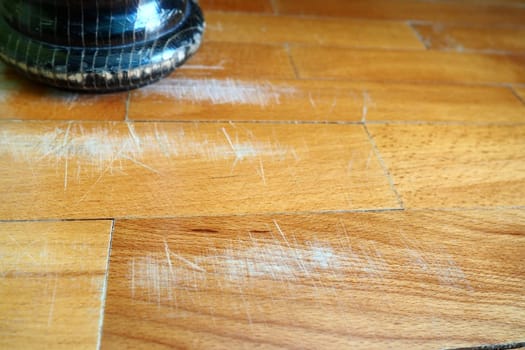Scratched old parquet flooring needs maintenance. The parquet is damaged by scratches from prolonged use. The leg of an antique wooden bed scratched the floor.