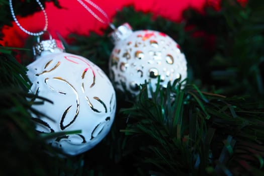 White silvery trendy Christmas balls with sprinkles and a pattern on Christmas tree branches. Postcard or New Year's Christmas background. Festive mood. Beautiful unusual decorations