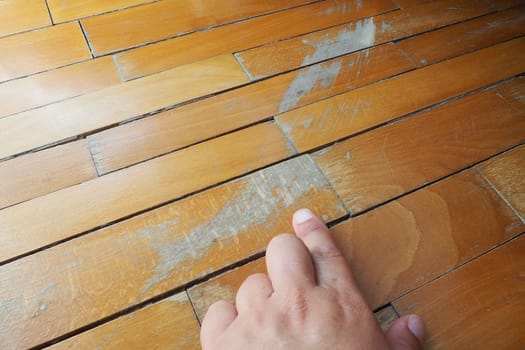 Old, scratched parquet flooring needs maintenance. the parquet is damaged by scratches from prolonged use. Master's hands show damage to the floor.