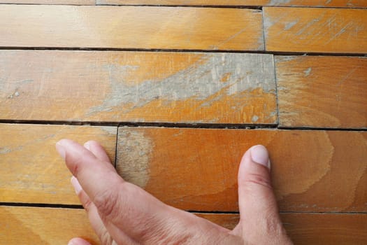 Old, scratched parquet flooring needs maintenance. the parquet is damaged by scratches from prolonged use. Master's hands show damage to the floor.