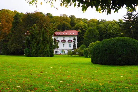 Banja Koviljaca, Serbia, Guchevo, Loznica, September 30, 2022 A medical building, the former royal villa. Green lawn in the park with flowers and bushes. Landscaping and decoration of the park area