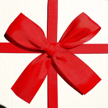 White gift box with red ribbon bow isolated on white background.