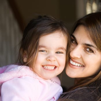 Caucasian mother holding daughter and smiling.