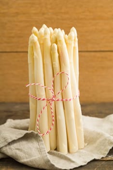 Bunch white asparagus on wooden table with linen cloth