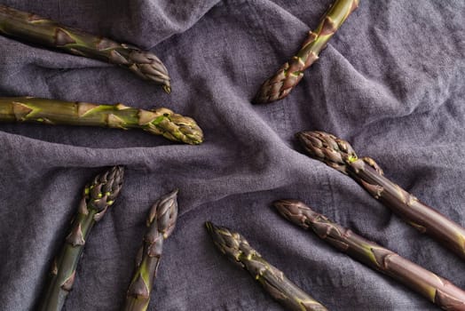 Fresh violet asparagus on dark linen in a dark light mood