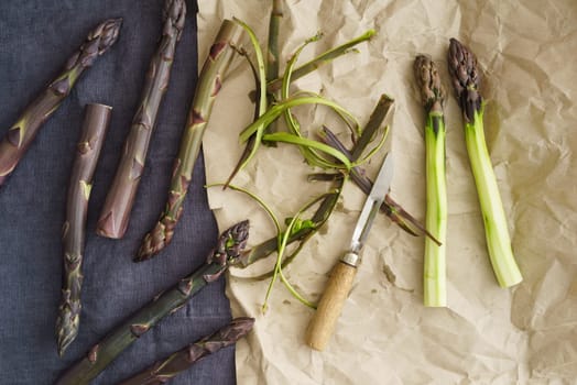Fresh violet asparagus on paper with old peeling knife