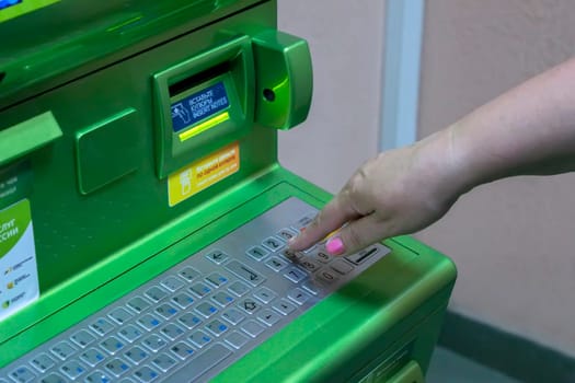 The hand of man (woman) is gaining PIN code on the keypad of the ATM terminal