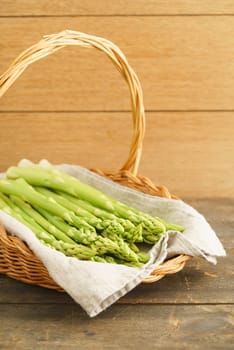 Fresh green asparagus in the shopping basket on a wooden table