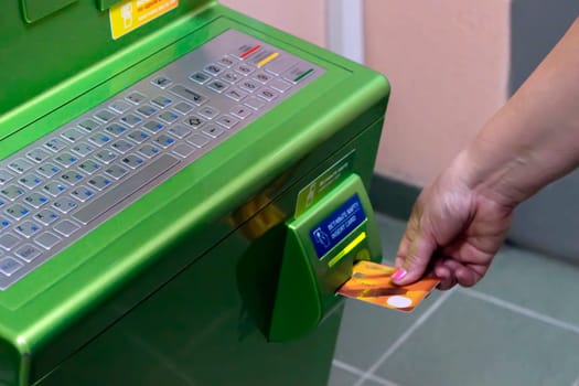 The hand of man (woman) inserts a plastic payment card in the ATM slot