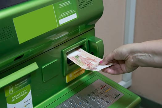 The hand of man (woman) insert a banknotes into a slot of the ATM.
