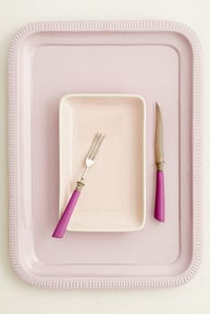 Small pink plate with pink cutlery on pink tray