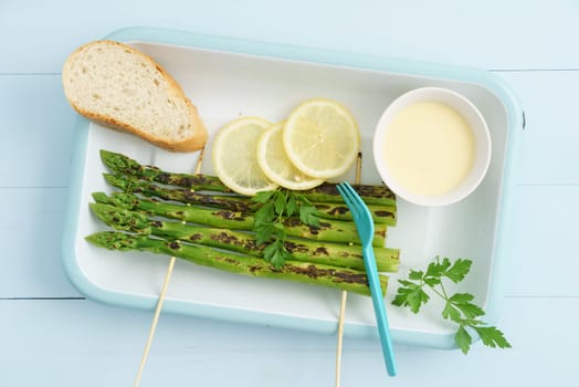 Grilled green asparagus skewers with Hollandaise sauce,baguette and lemon