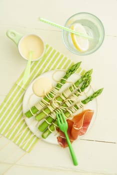 Steamed green asparagus on wood skewers with spaghetti wrapped with Hollandaise sauce and ham