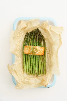 Baked green asparagus with salmon with baking paper in a blackening dish