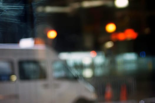 Abstract and fuzzy brake lights and light circles behind a window pane.