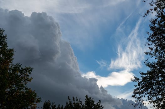 Large dark clouds are gathering with blue skies and green trees