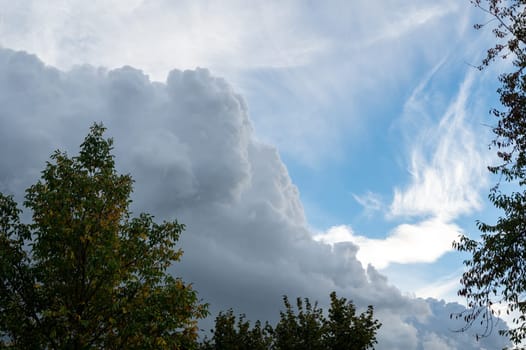 Large dark clouds are gathering with blue skies and green trees