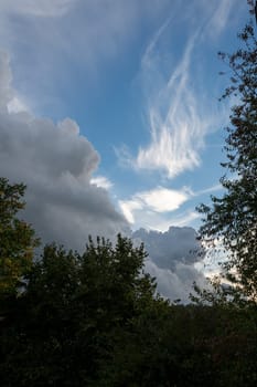 Large dark clouds are gathering with blue skies and green trees