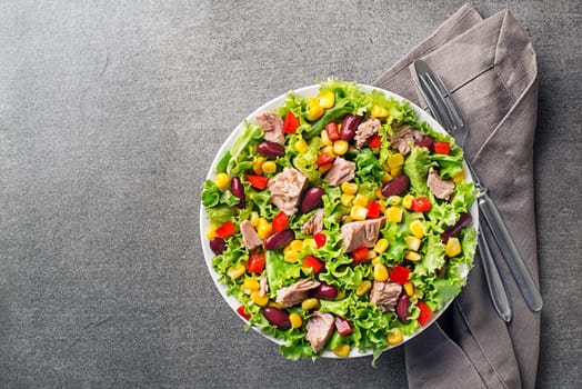Healthy Green salad with tuna, corn, red pepper and beans on grey table background. Mexican corn salad.