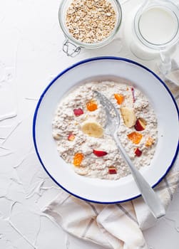 Oatmeal plate. A plate of oatmeal served with fresh fruit and milk. Healthy food, diet. Top view.
