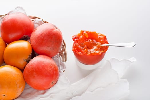 Ripe red and yellow orange persimmon fruit.Slices of persimmon. Close up of fresh kaki on white table