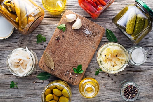 Canned and pickled vegetables in glass jars on wooden table. Preserved food
