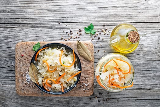 Homemade sauerkraut with carrot in a glass jar on a rustic background. Fermented product.