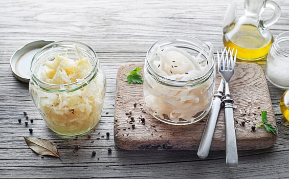 Traditional fresh and healthy sauerkraut and sour turnip in glass jar on wooden background.