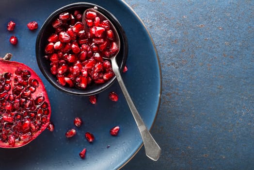Healthy ripe pomegranate fruit opened and split with seeds on white plate