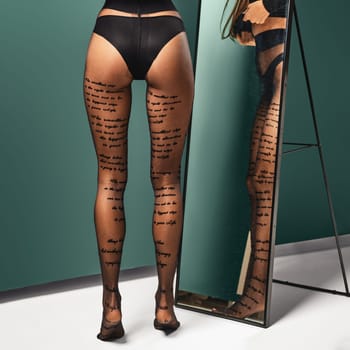 Beautiful female legs in pantyhose with inscriptions in front of the mirror
