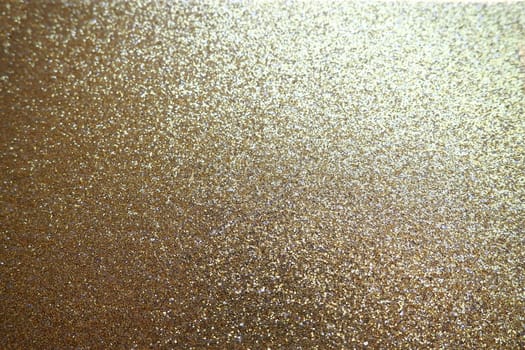 Gold close up. Golden glitter texture background. Sparkling glitter wrapping paper with sequins and sparkles. Festive golden bokeh and glitter. Beautiful background. Bokeh light of gold glitters.