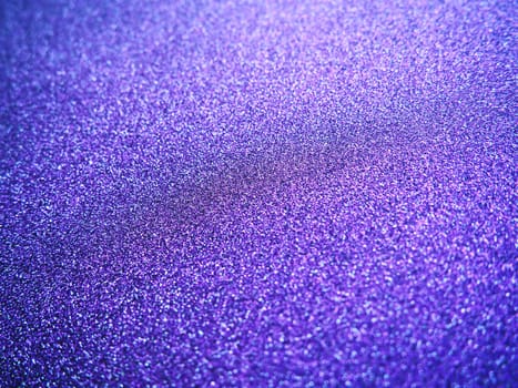 Deep blue. Texture of rough paper or cardboard. Defocused bokeh sparkles and shining. Festive blue background with illuminated sapphire gradient.