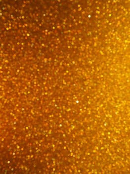 Bokeh light of gold glitters. Golden glitter texture background. Sparkling glitter wrapping paper with sequins and sparkles. Festive golden bokeh and glitter. Beautiful background