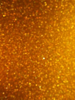 Bokeh light of gold glitters. Golden glitter texture background. Sparkling glitter wrapping paper with sequins and sparkles. Festive golden bokeh and glitter. Beautiful background