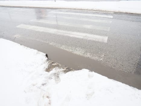 Snow, ice, slush and winter mud at a pedestrian crossing. The air temperature is about 0. Difficult driving conditions. Braking distance of the car. Traffic Laws. Infrastructure and road services.