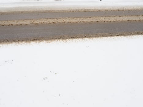 Snowdrifts on the side of the road. Bad weather and traffic. Snow on asphalt. Difficult driving conditions. Winter slosh on the road. Braking distance of a car
