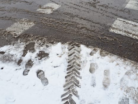 A fork or siding from a roundabout. Snowdrifts on the side of the road. Bad traffic weather. Footprints in the snow. Difficult driving conditions. Winter slosh on the road. Braking distance of a car